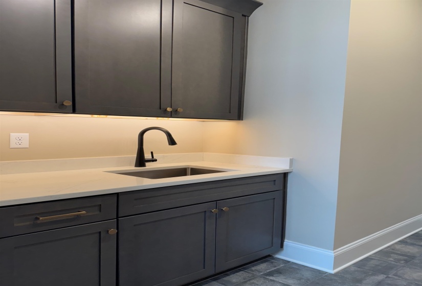 Bar area with gray cabinets and light stone countertops