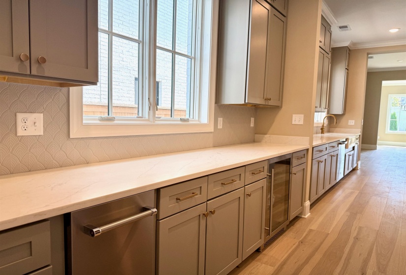 Kitchen with gray cabinets, crown molding, light stone countertops, light wood-style floors, and wine cooler