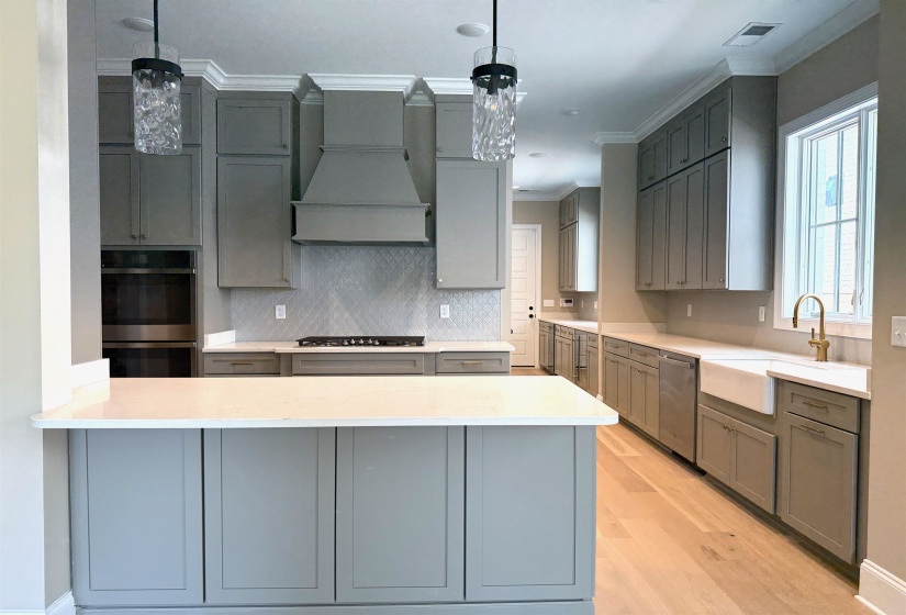 Kitchen with gray cabinets, backsplash, crown molding, stainless steel appliances, and a peninsula