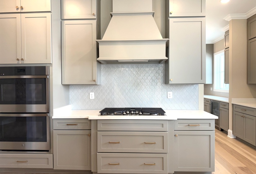 Kitchen featuring stainless steel appliances, gray cabinets, tasteful backsplash, premium range hood, and ornamental molding