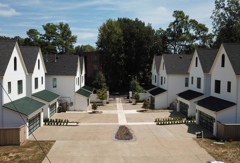 View of property exterior featuring a residential view, brick siding, driveway, and a shingled roof