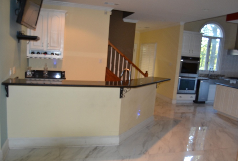 Kitchen with dark countertops, light marble finish floors, open shelves, double oven, and ornamental molding