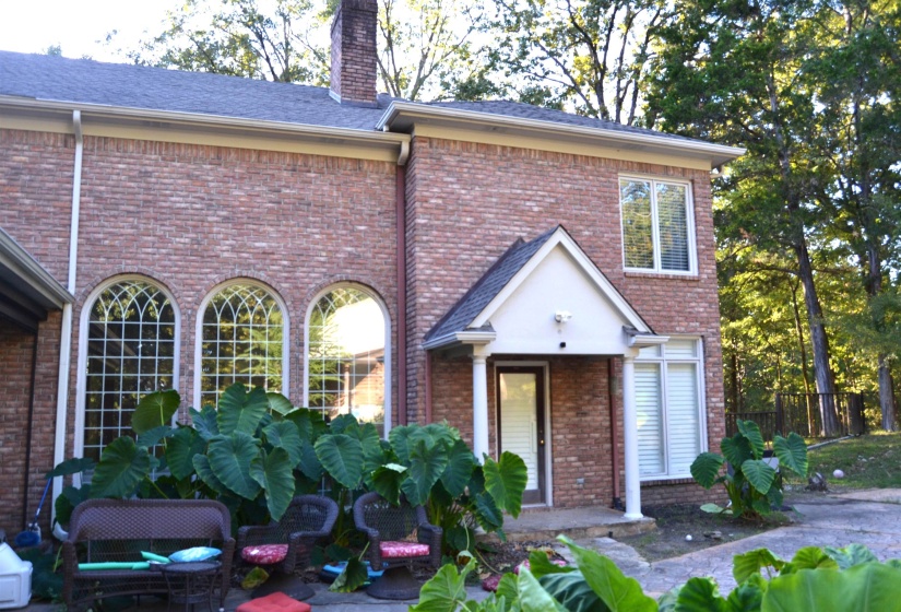 View of rear of house with brick siding, a chimney, and roof with shingles