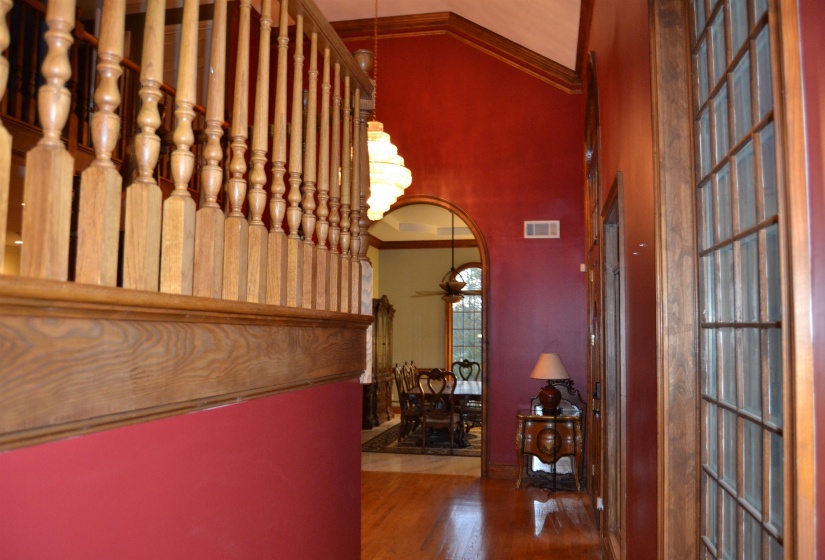 Corridor featuring ornamental molding, wood finished floors, a chandelier, and arched walkways