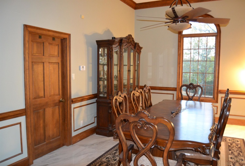 Dining space featuring light marble finish flooring, wainscoting, ceiling fan, and crown molding