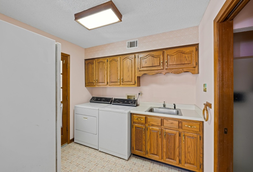 Featuring upper and lower cabinets along with a convenient sink, this laundry room is designed for maximum efficiency. The layout allows for easy workflow, keeping the space tidy while providing plenty of room for all your household needs.