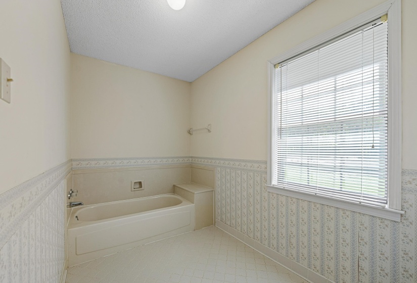 A built-in bathtub creates a cozy place to soak and unwind, complemented by a convenient shelf behind for easy access to essentials. The space invites relaxation and offers the perfect foundation for future customization.