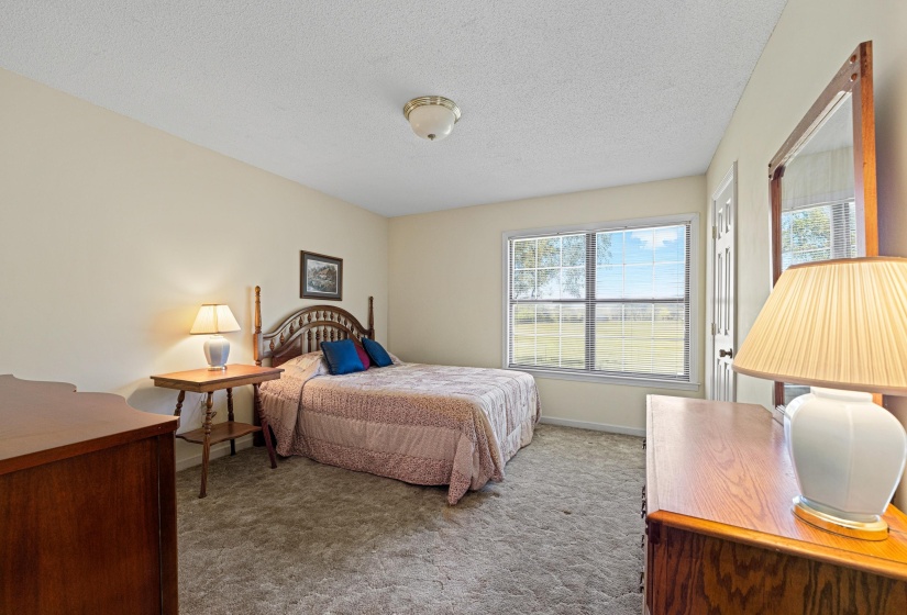 With abundant natural light from the large window and soft carpet underfoot, this bedroom offers a cozy, inviting environment. The room's airy feel makes it perfect for rest, reading, or quiet reflection.