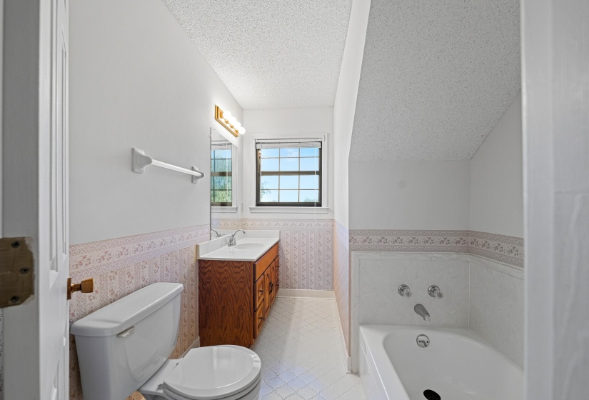 This bathroom features a tub, single-sink vanity, and tile flooring. Its efficient layout maximizes space while providing a clean and functional setting for daily use.