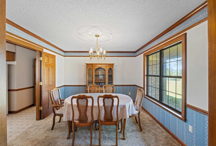 This formal dining room features a large window overlooking the front yard, filling the space with natural light. Open to the kitchen, it provides effortless flow for entertaining, making it easy to serve meals while staying connected.