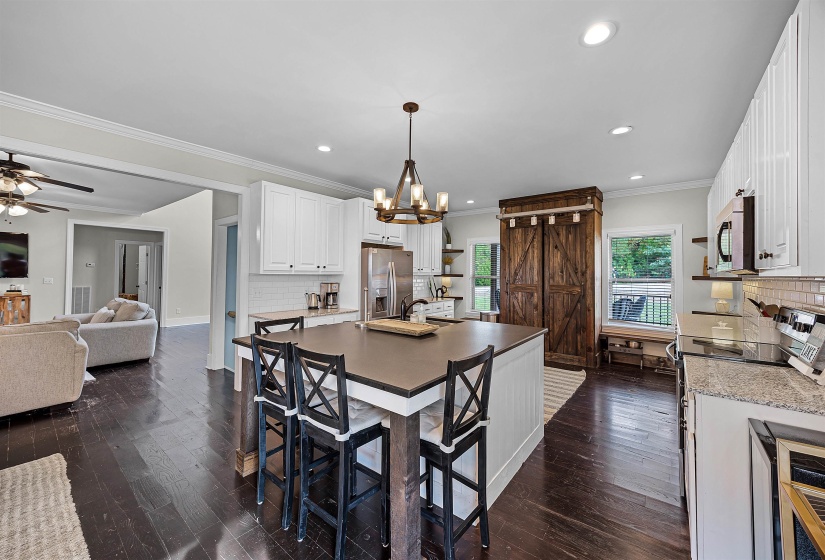 Kitchen with decorative backsplash, white cabinetry, ornamental molding, dark wood-type flooring, and hanging light fixtures