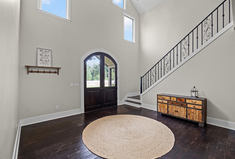 Entrance foyer with healthy amount of natural light, arched walkways, a towering ceiling, dark wood finished floors, and stairway