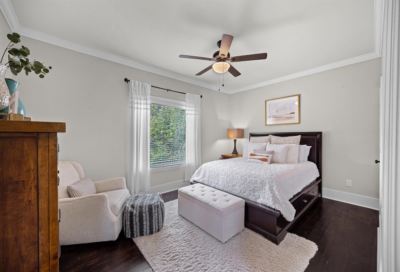 Bedroom featuring ornamental molding, dark wood-style floors, and a ceiling fan