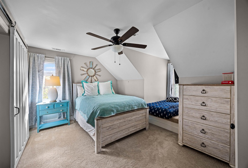 Bedroom with multiple windows, light carpet, vaulted ceiling, and a ceiling fan