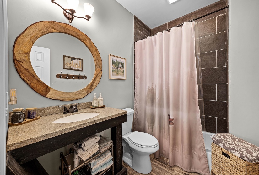 Full bath featuring shower / tub combo with curtain and wood finished floors