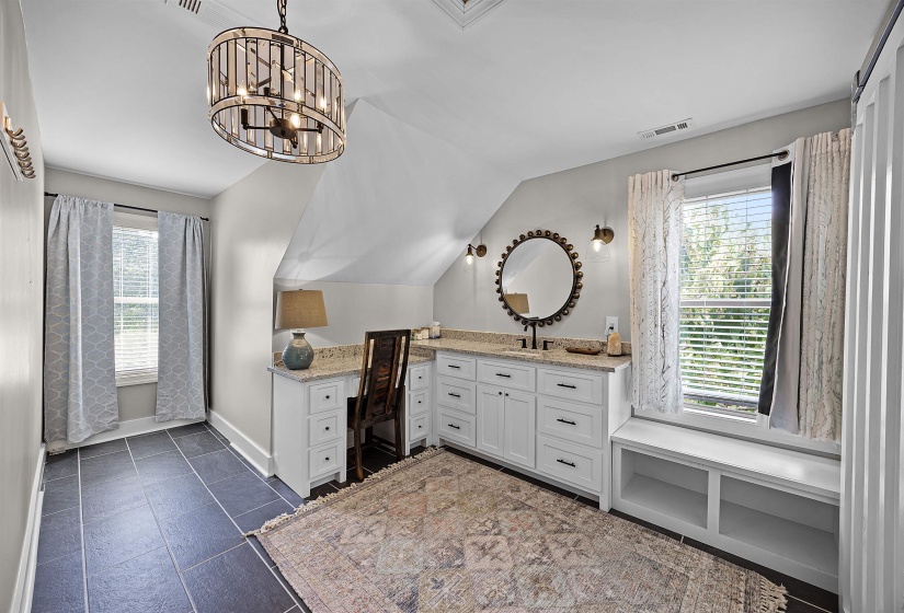 Bathroom featuring vanity, lofted ceiling, dark tile patterned flooring, and a chandelier