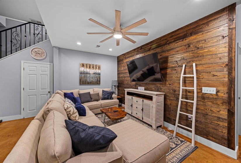Living area with wooden walls, ceiling fan, recessed lighting, an accent wall, and light wood-style flooring