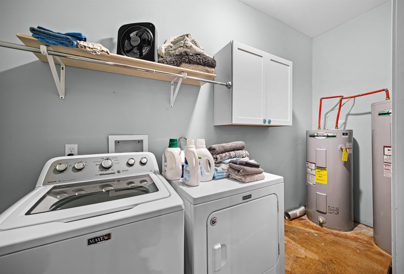 Laundry room featuring electric water heater, cabinet space, and independent washer and dryer