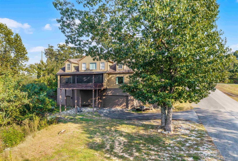 Back of property with a sunroom, driveway, a lawn, and a garage