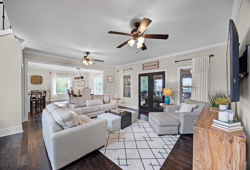 Living area featuring ornamental molding, dark wood-style floors, ceiling fan, and french doors