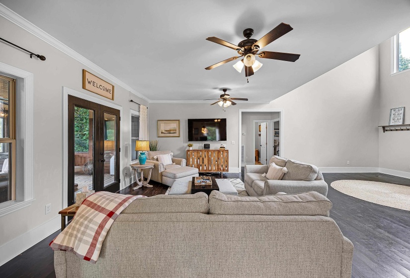 Living room featuring dark wood finished floors, ceiling fan, french doors, and crown molding
