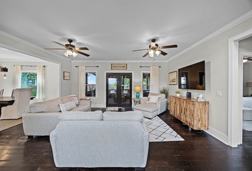 Living area featuring a ceiling fan, ornamental molding, dark wood-style floors, and french doors