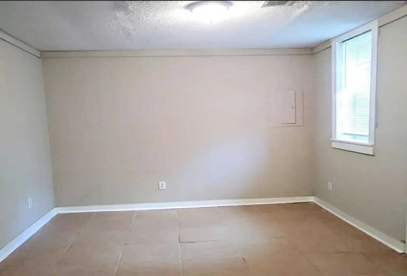 Tiled empty room featuring a textured ceiling and electric panel