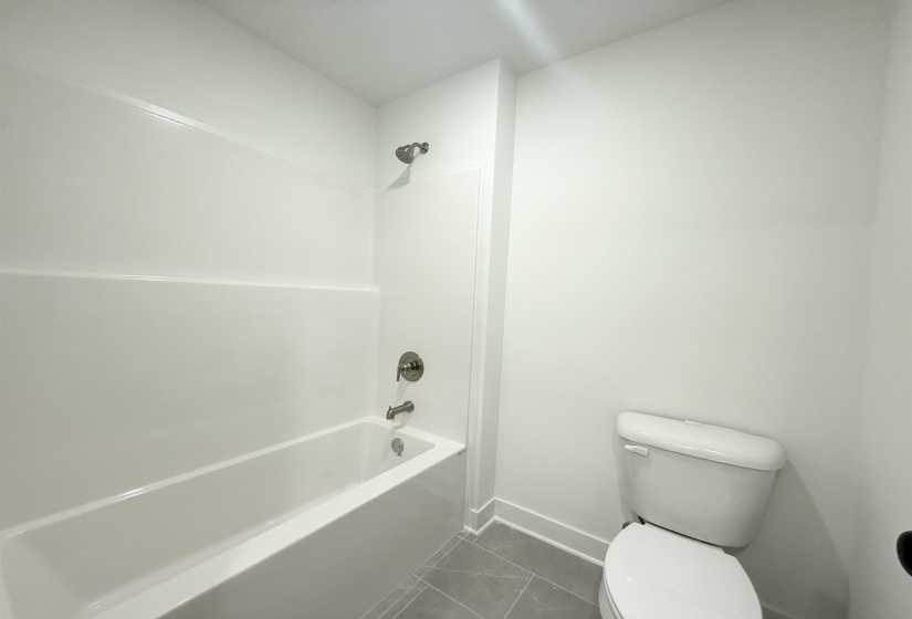 Bathroom featuring tub / shower combination and dark tile patterned floors