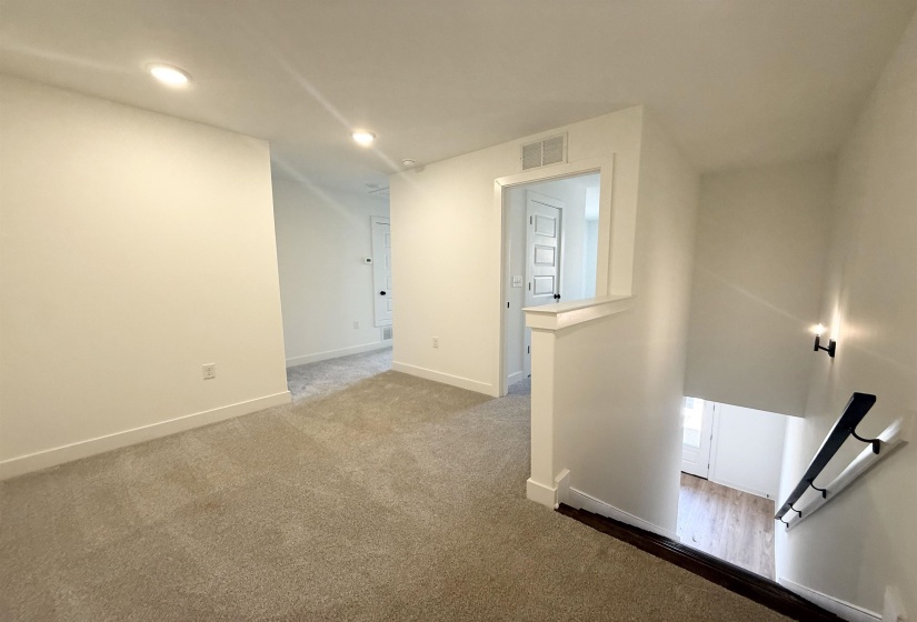 Hallway featuring an upstairs landing, dark colored carpet, and recessed lighting