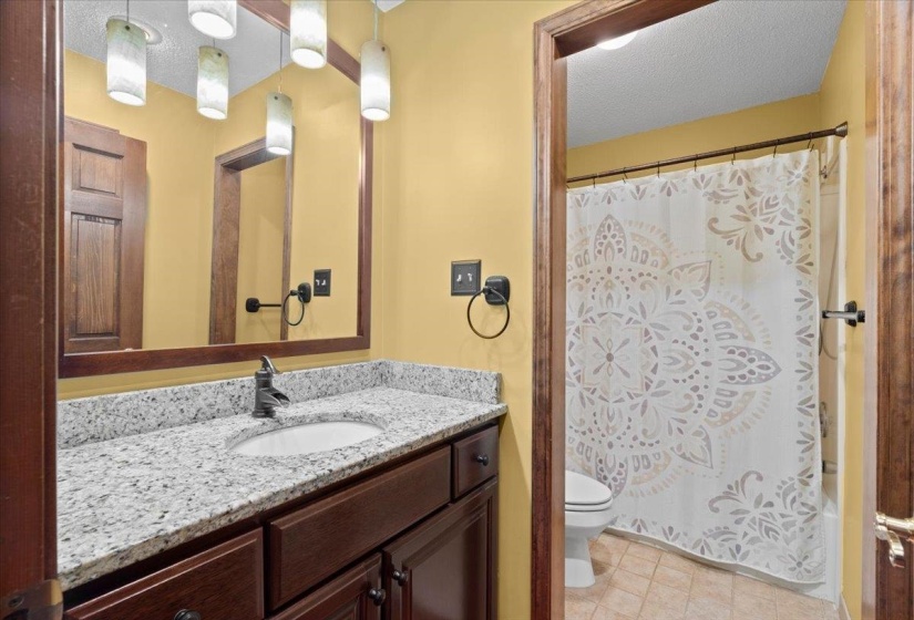 Full bathroom featuring a textured ceiling, vanity, shower / bath combo with shower curtain, and light tile patterned floors