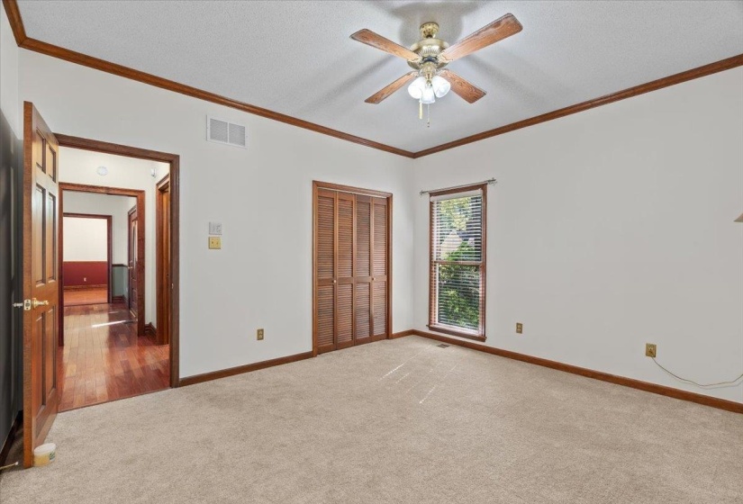 Unfurnished bedroom with crown molding, carpet floors, a closet, a ceiling fan, and a textured ceiling