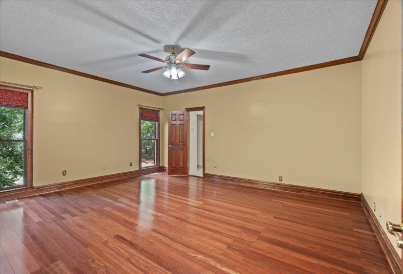 Unfurnished room featuring wood finished floors, a textured ceiling, ornamental molding, and ceiling fan