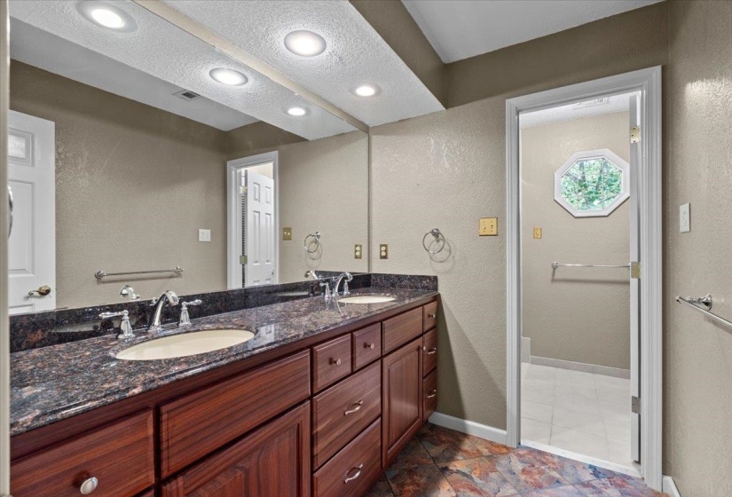Bathroom with a textured wall, double vanity, and a textured ceiling