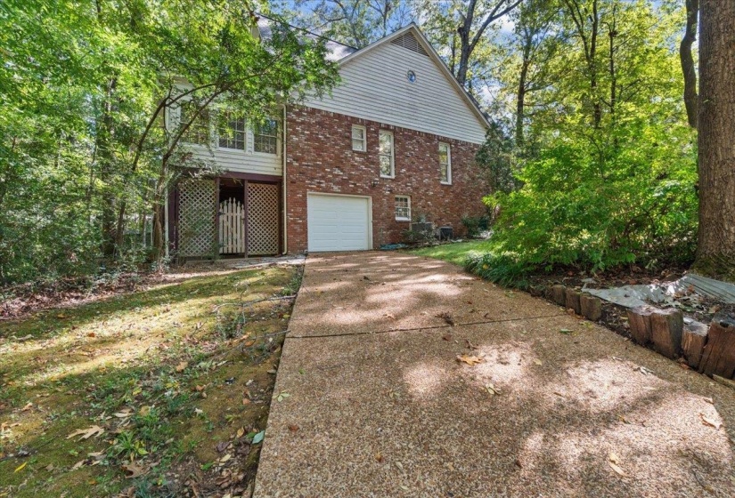 View of home's exterior featuring driveway, an attached garage, brick siding, and a balcony