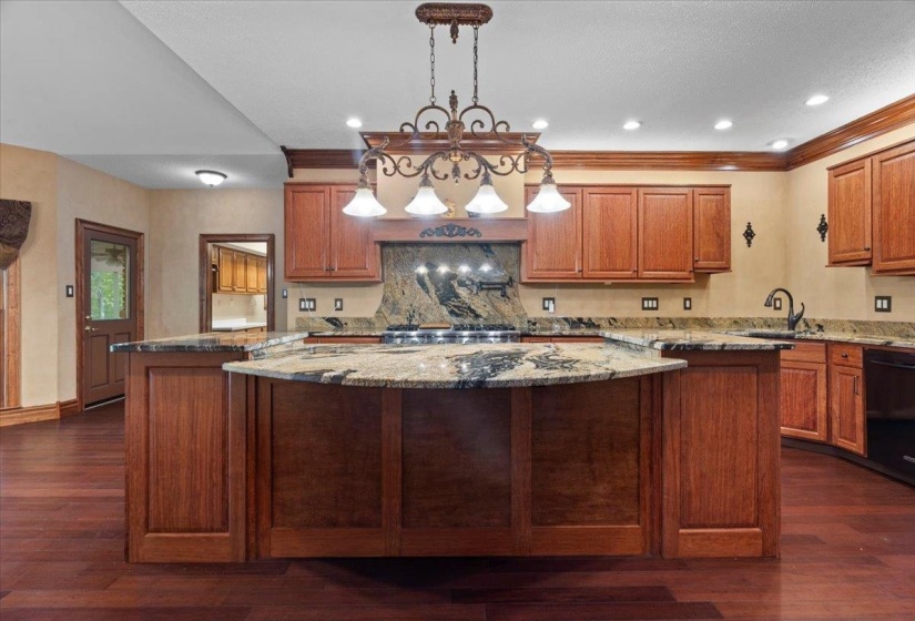 Kitchen featuring light stone countertops, brown cabinets, a center island, pendant lighting, and dishwasher