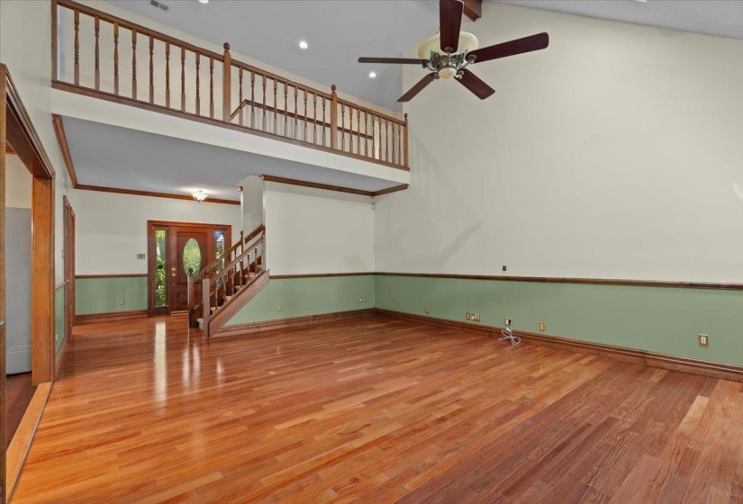 Unfurnished living room featuring high vaulted ceiling, light wood finished floors, and stairs
