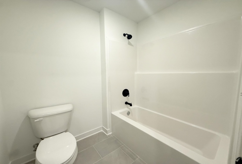 Bathroom with dark tile patterned flooring and tub / shower combination