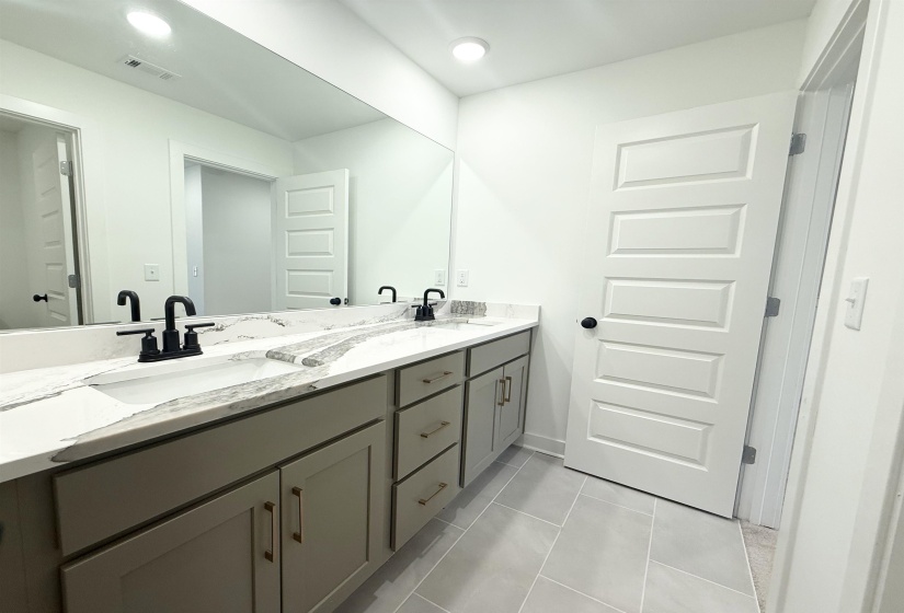 Bathroom with double vanity, recessed lighting, and light tile patterned floors