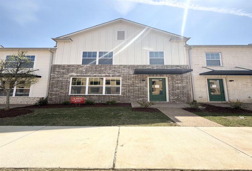 View of front facade featuring board and batten siding, brick siding, and a front yard