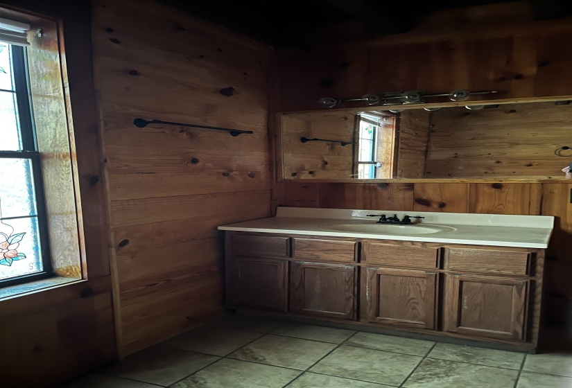 Half bathroom with wooden walls, vanity, and light tile patterned flooring