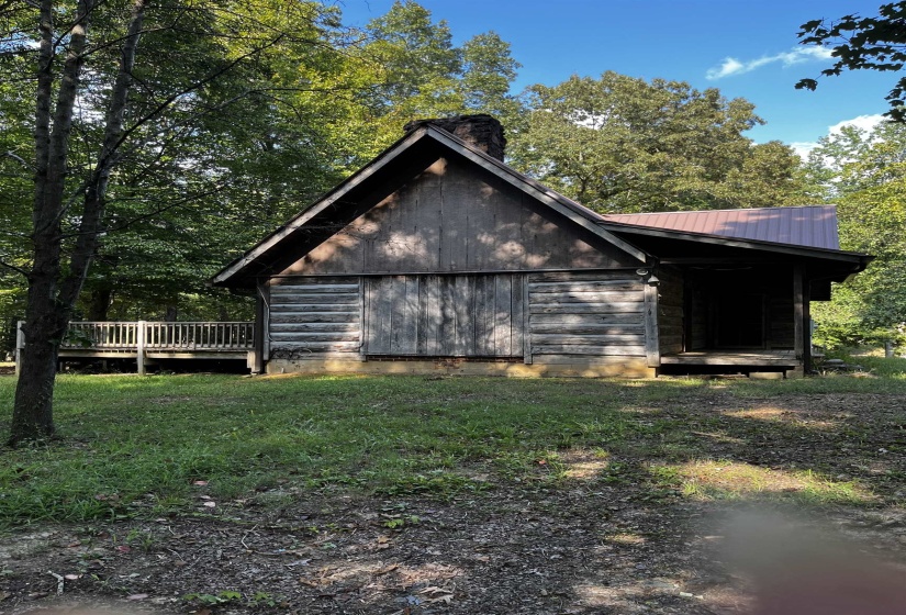 View of side of home with a metal roof, a chimney, and a lawn