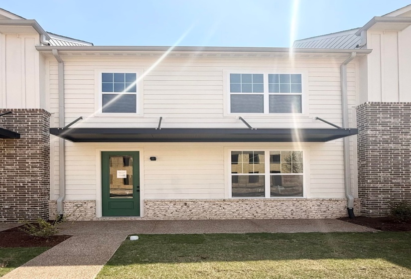 View of front of house with board and batten siding, a front yard, and a metal roof