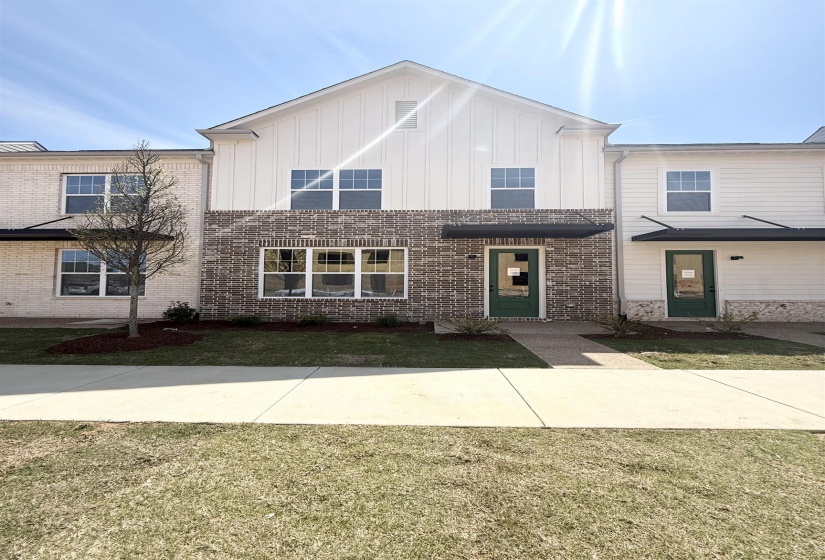 View of front of house featuring board and batten siding, brick siding, and a front lawn