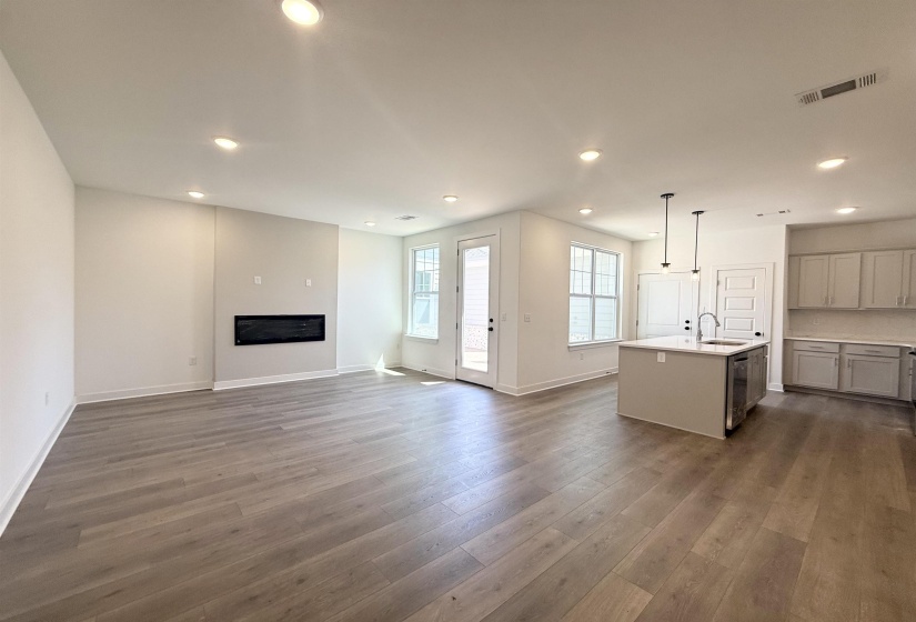 Unfurnished living room featuring recessed lighting, dark wood-style flooring, and a glass covered fireplace
