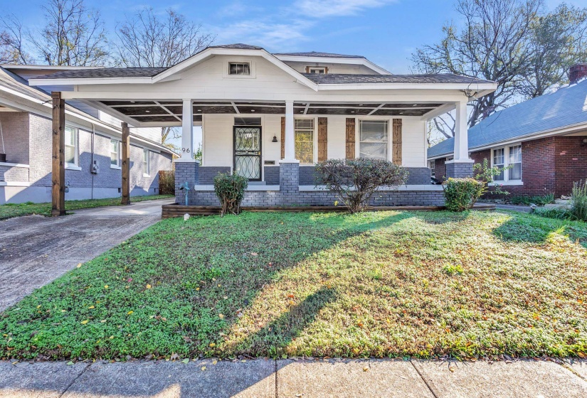 View of front of home with a porch, a front lawn, brick siding, driveway, and roof with shingles