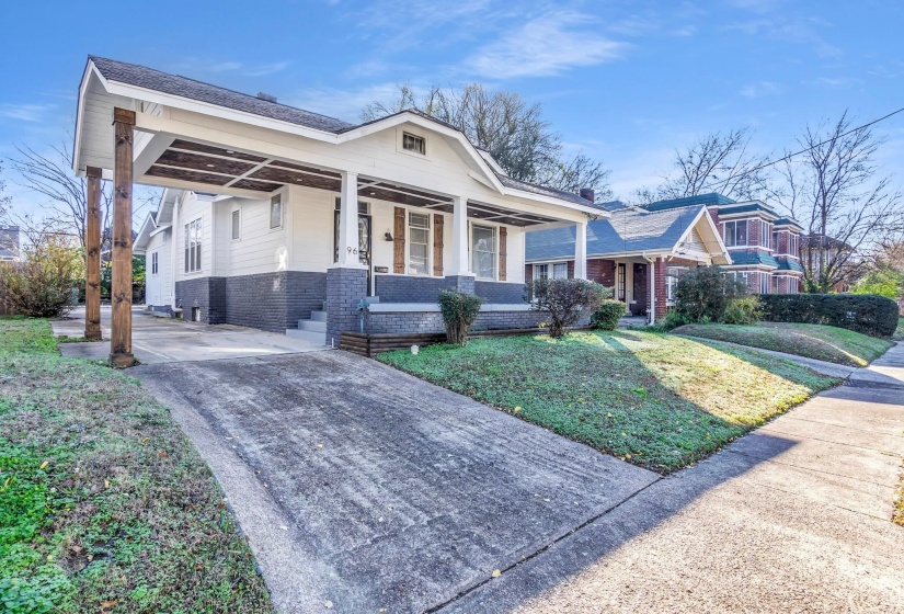 View of front of house featuring covered porch, brick siding, a front lawn, and driveway
