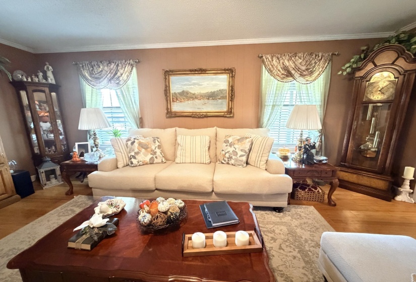 Living area with wood finished floors, crown molding, and healthy amount of natural light