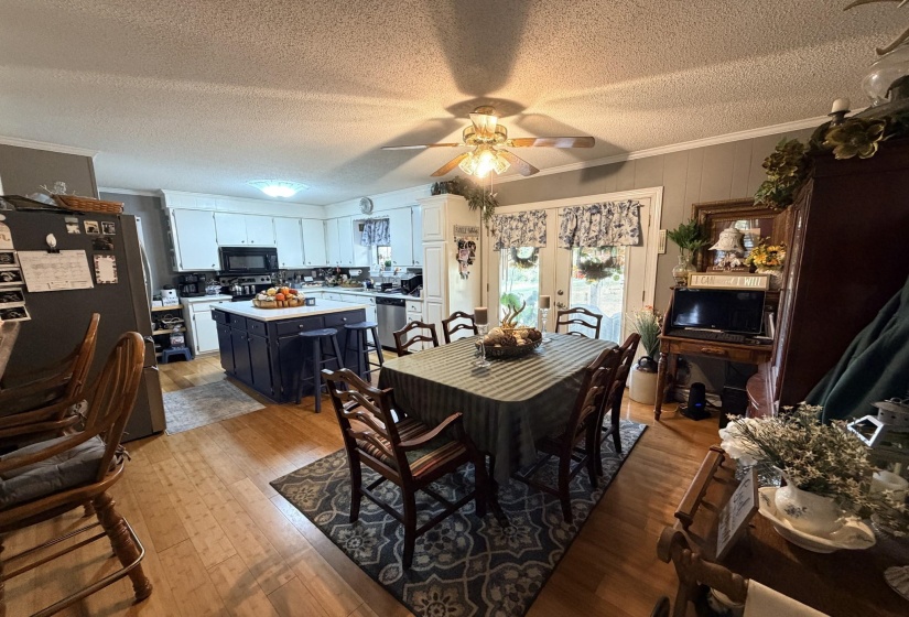 Dining room featuring crown molding, light wood-style floors, a textured ceiling, ceiling fan, and french doors