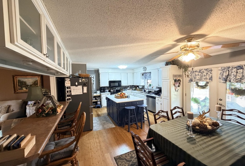 Dining space with a textured ceiling, light wood finished floors, a ceiling fan, crown molding, and french doors