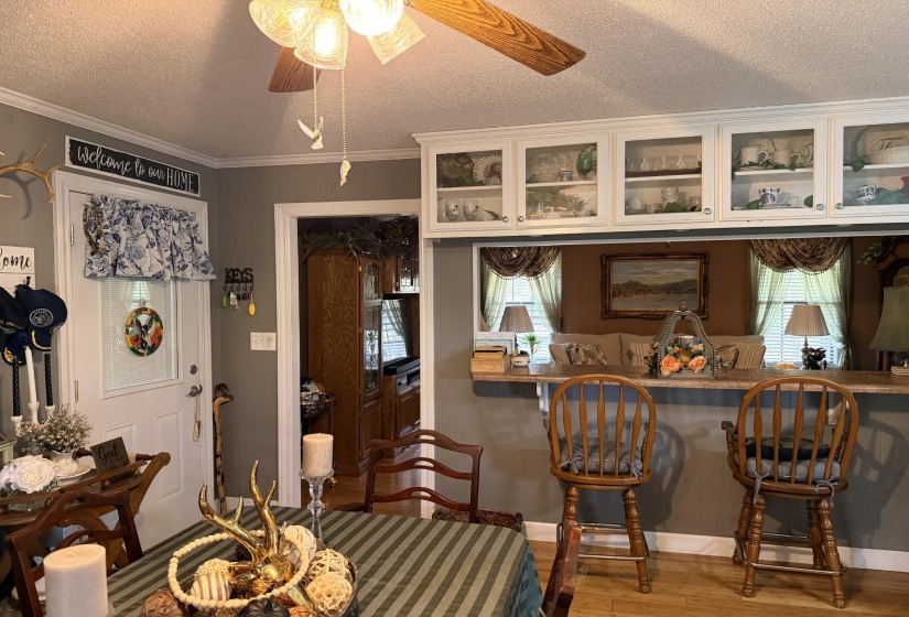 Dining space with a textured ceiling, wood finished floors, crown molding, plenty of natural light, and a ceiling fan
